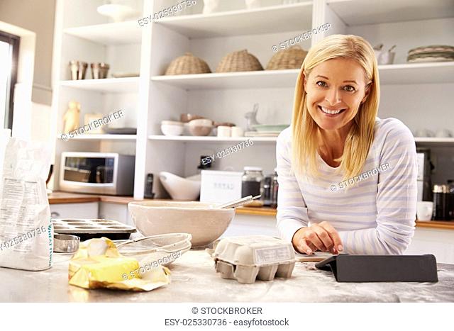 Woman baking at home following recipe on a tablet