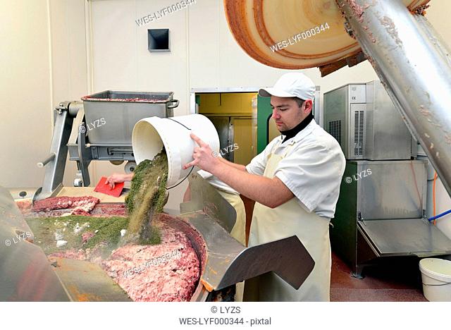 Man pouring spices into silent cutter in a butchery