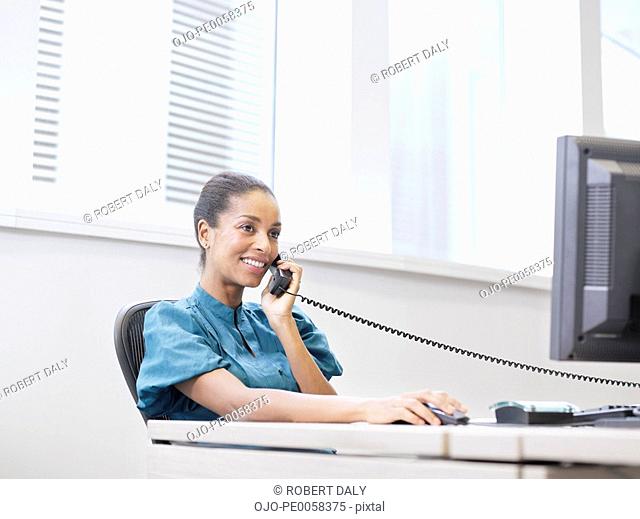 Businesswoman on the telephone at a computer in an office