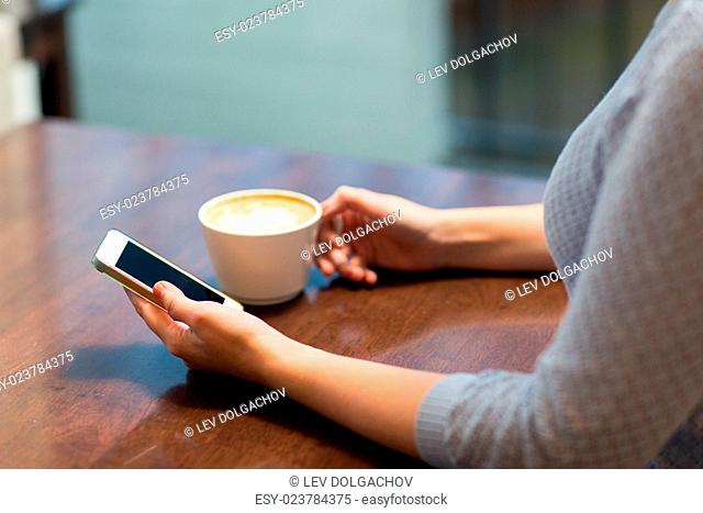 drinks, people, technology and lifestyle concept - close up of young woman with smartphone drinking coffee at cafe