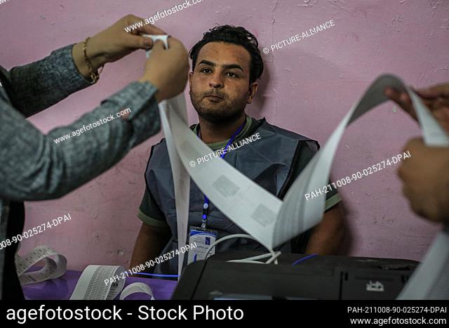 08 October 2021, Iraq, Baghdad: Iraqi employees prepare the official paper that includes the number of voters before handing it to the observers of the...