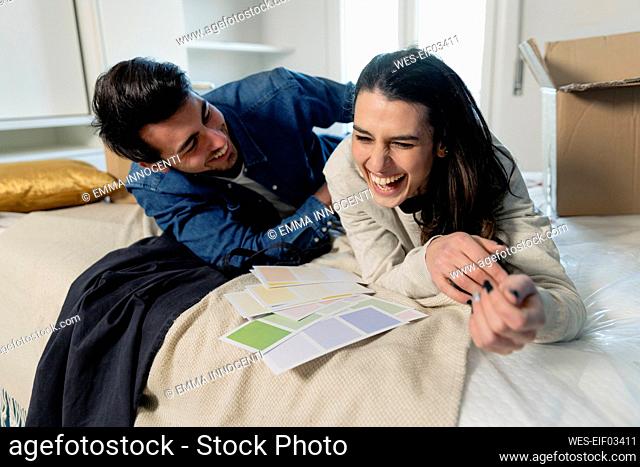 Cheerful young couple choosing color swatches in bedroom at new home