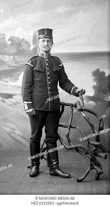 An army lance-corporal in uniform and boots with spurs, Landskrona, Sweden, 1910. Posed against a backdrop in a photographer's studio