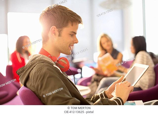 University student using digital tablet in lounge