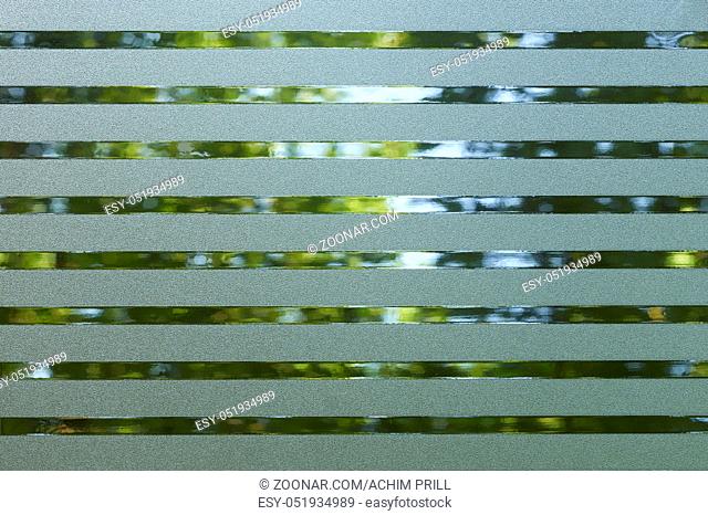 full frame abstract blue green lined translucent plastic foil in front of vegetation background