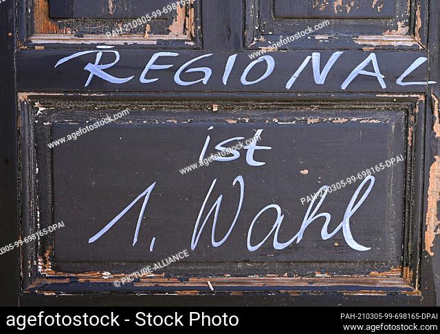 02 March 2021, Brandenburg, Hohenfinow: A slogan ""Regional is 1st choice"" is written on an old door on the grounds of the Barnimer Brauhaus