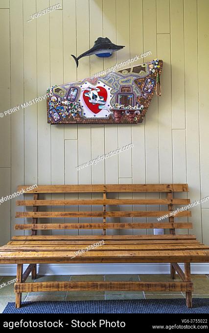 Wood plank sitting bench and Volkswagen hood panel decorated with Canadian and U. S. pennies and dollar store objects by folk art artist David Stephens in...