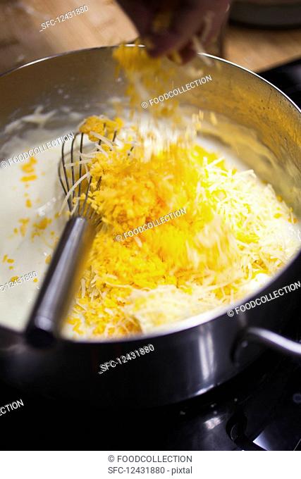A cook preparing cheese sauce for making macaroni cheese