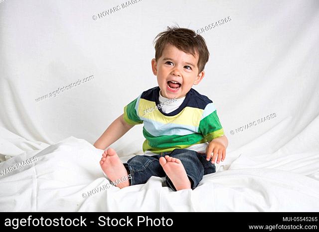 Little boy is sitting on a bed