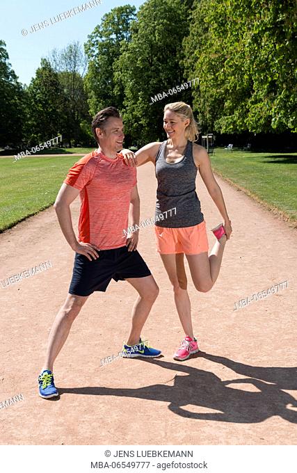 Couple in sportswear on track in the park, stretching exercise, stretching