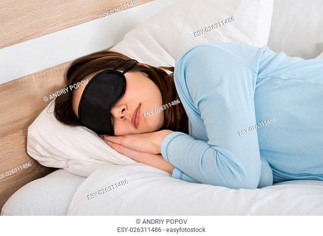 Young Woman Sleeping With Eyemask On Bed
