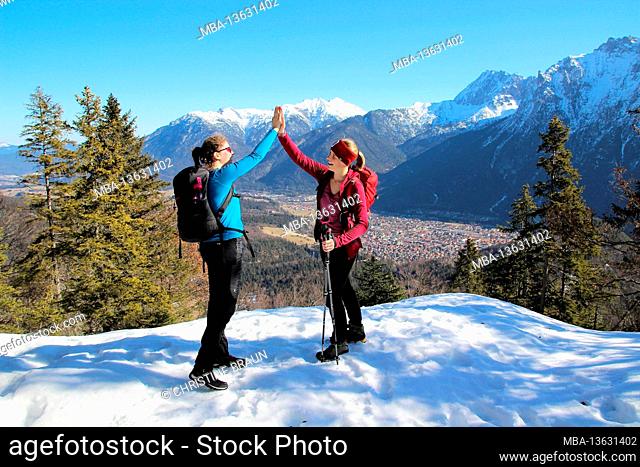 Winter hike 2 women to the Grünkopf near Mittenwald, Europe, Germany, Bavaria, Upper Bavaria, Isar Valley, clapping on a mountain peak