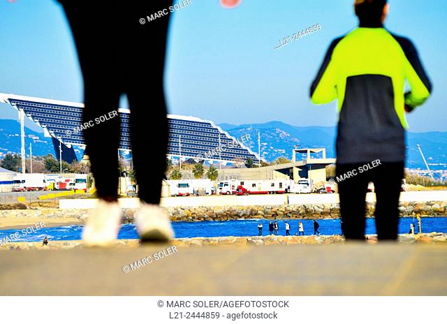 First, blurred figures of people dressed in sportswear. In the background, photovoltaic pergola by architects Elías Torres and José Antonio Lapeña at Forum Park