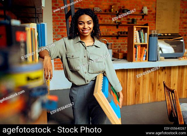 Female student poses at the shelf in university library. Woman at bookshelf, education and knowledge. Girl studying in campus