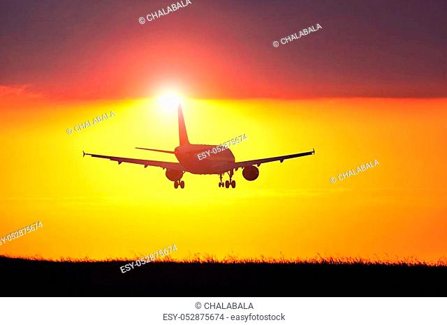 Airplane landing at the airport during amazing sunset
