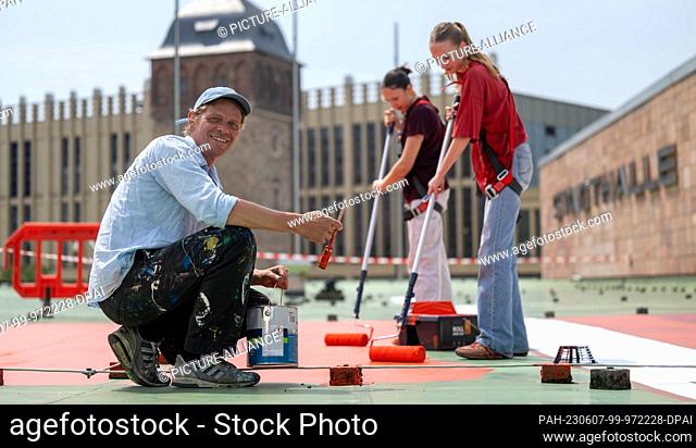 07 June 2023, Saxony, Chemnitz: The Belgian artist Larsen Bervoets (l-r) is supported by the students Lina Römer and Anna Taube in the work for his artwork on...