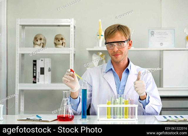 Young Brazilian scientist with a safety glasses lab is mixing cosmetic chemicals together carefully. Working atmosphere in chemical laboratory