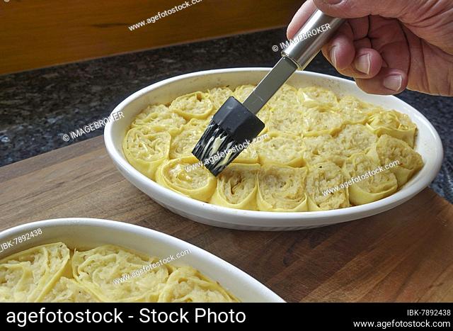 Swabian cuisine, preparation of Krautkrapfen, flour sacks, sauerkraut in pasta patties, buttering pasta dough pieces in casserole dish, brush, hearty, healthy