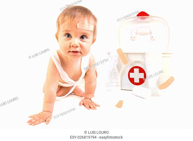 Cute baby boy playing with bandages in a first aid kit box