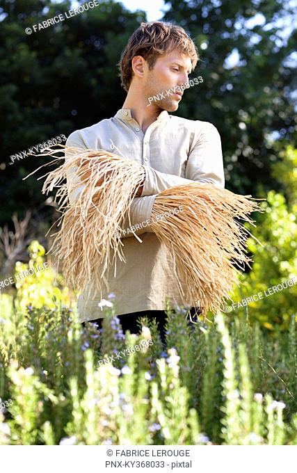 Young man standing in a field as scarecrow