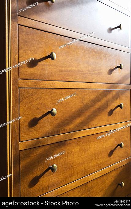 Maple wood dresser with brass metal knobs on drawers in guest bedroom inside an old 1807 cottage style house, Quebec, Canada