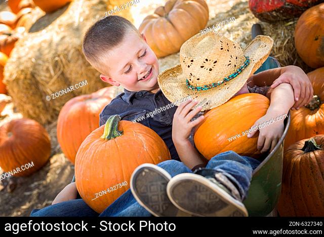Two Little Boys Playing in Wheelbarrow at the Pumpkin Patch in a Rustic Country Setting