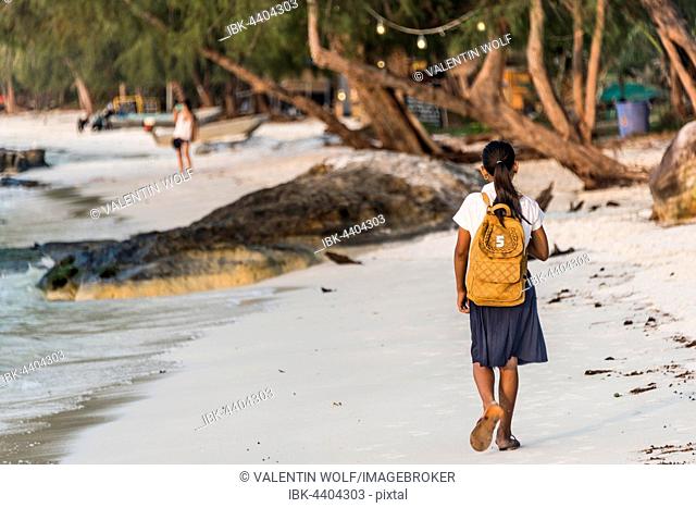 Local girls walking to school on idyllic sandy beach at Koh Tui Beach, Koh Touch village, Koh Rong island, Krong Preah Sihanouk, Sihanoukville, Cambodia