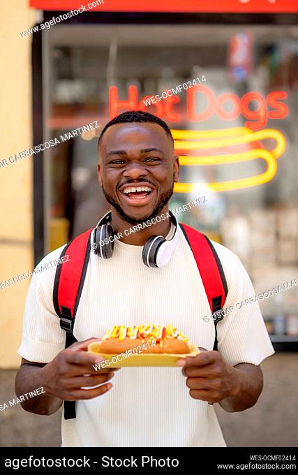 Happy young man holding hot dog