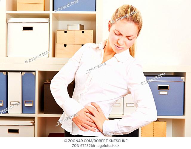 Junge Frau im Büro hat Rückenschmerzen und hält sich die Taille
