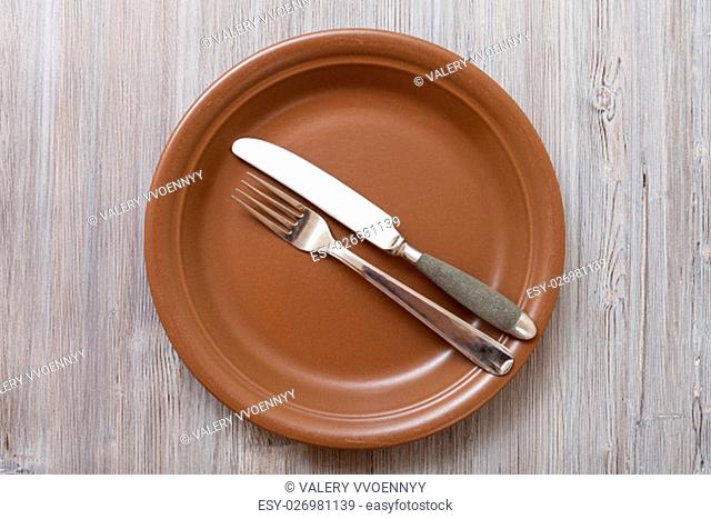food concept - top view of brown plate with parallel knife, spoon on gray brown table