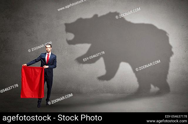 Businessman standing with red cloth in his hand and big bear shadow on his background