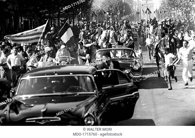 The enthusiasm of the crowd at the passing of the presidential parade for Giovanni Gronchi. Along a street in Montevideo crowds of people run after the elegant...