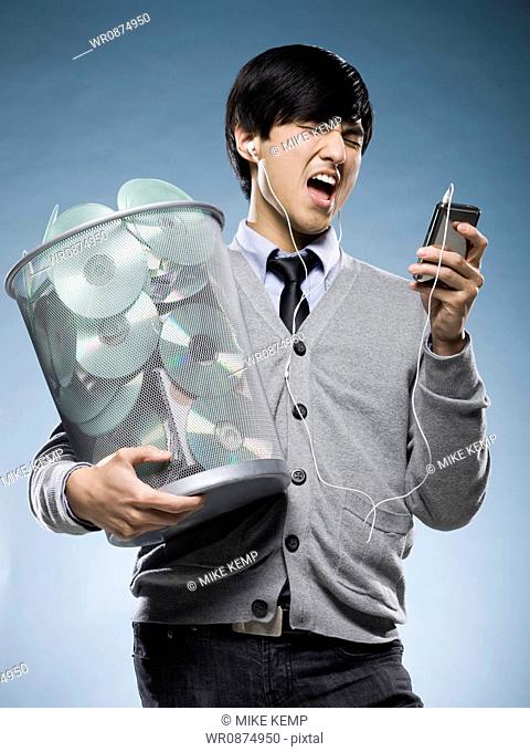 man with a trash can full of cds and holding an iPod