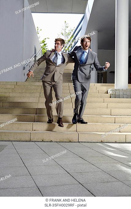 Businessmen walking arm-in-arm on steps