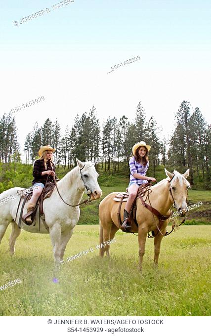 Two teen girls riding horses in Reardan, Washington, USA