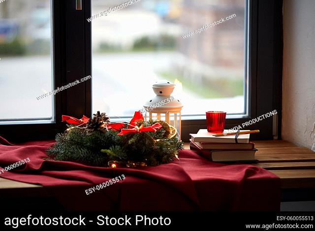 christmas wreath, books, candle, lantern on window