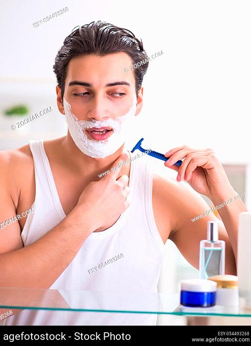 The young handsome man shaving early in the morning at home