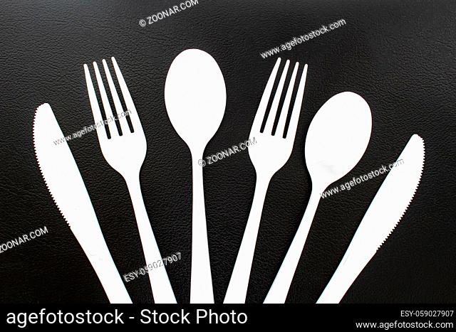 Single use white plastic cutlery on a leather background. Concept: Ban single use plastic