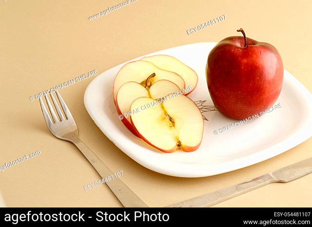 Delicious apple and slice in white plate with knife and fork