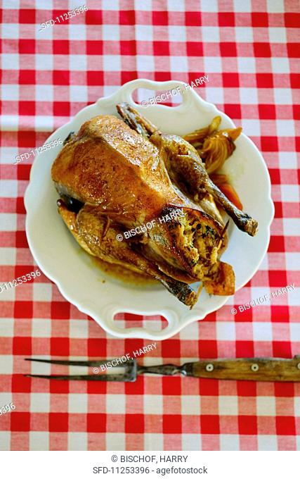 A stuffed roast chicken on a plate