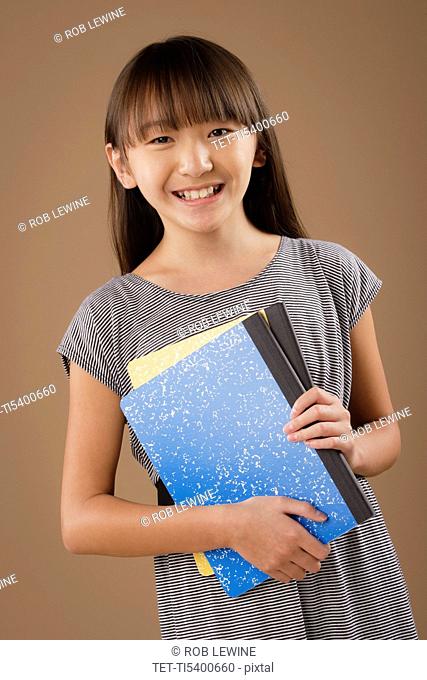 Studio portrait of girl 10-11 holding book