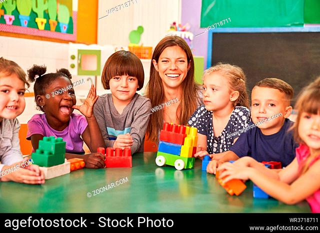 Fröhliche Kinder in der Vorschule oder im internationalen Kindergarten mit Kindergärtnerin