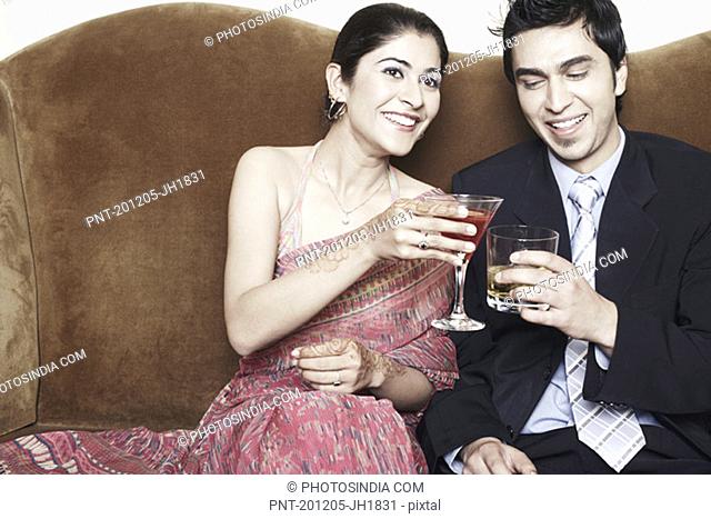 Young couple toasting with martini and whiskey glasses