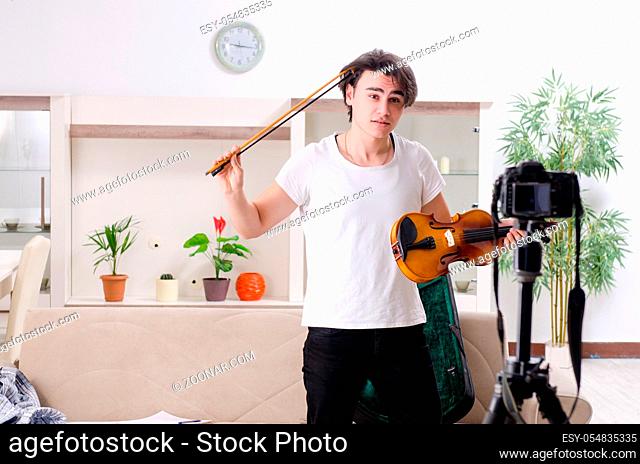 The young male blogger playing violin at home