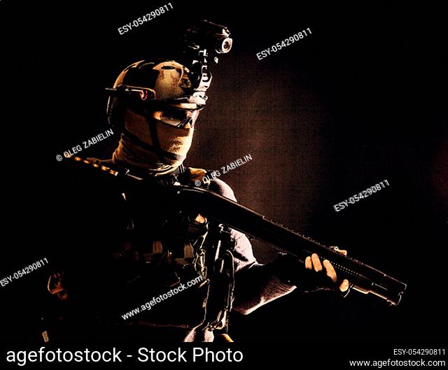 Shoulder portrait of army elite troops soldier, anti-terrorist tactical team wit shotgun, helmet with thermal imager, hiding face behind mask