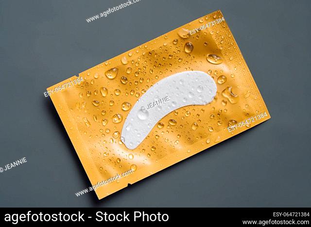 Bright yellow package of moisturizing, nourishing patches undereyes lies on dark gray background. Beauty and health. Natural substances in cosmetology