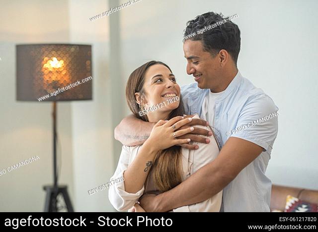 Love and tenderness young adult interracial couple at home. Concept of new house and life together with boy and girl hugging and smiling together with love and...