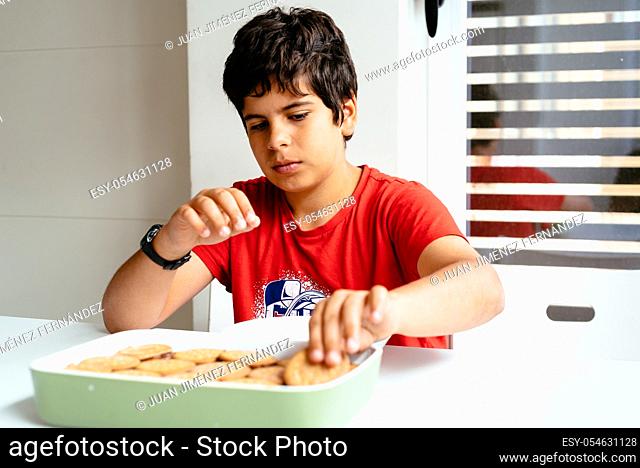 Close up of hands of child preparing homemade chocolate cake made with biscuits