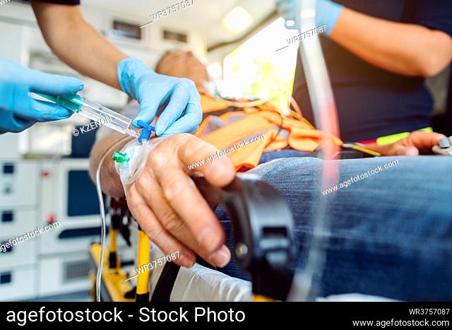 Emergency doctor administering injection needle in ambulance, closeup shot