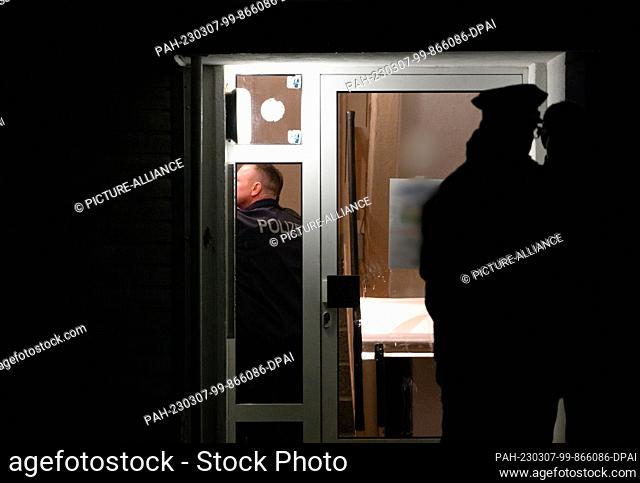 07 March 2023, Brandenburg, Senftenberg: Police officers stand in the hallway of an apartment building and in front of the front door